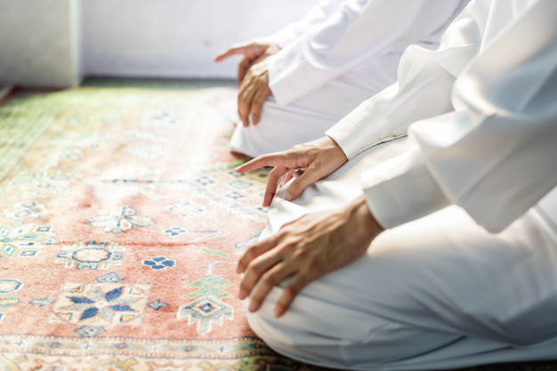 Muslim men praying in tashahud 