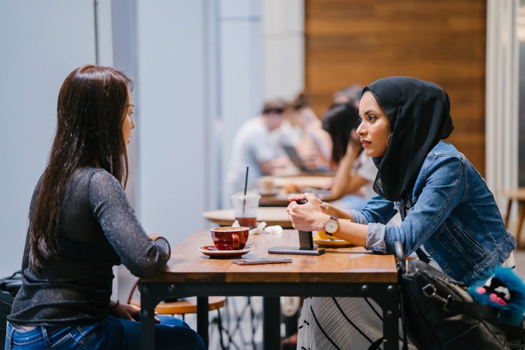 Muslim woman sitting with friend in cafe.