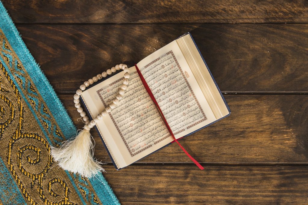 Beads and opened quran near mat