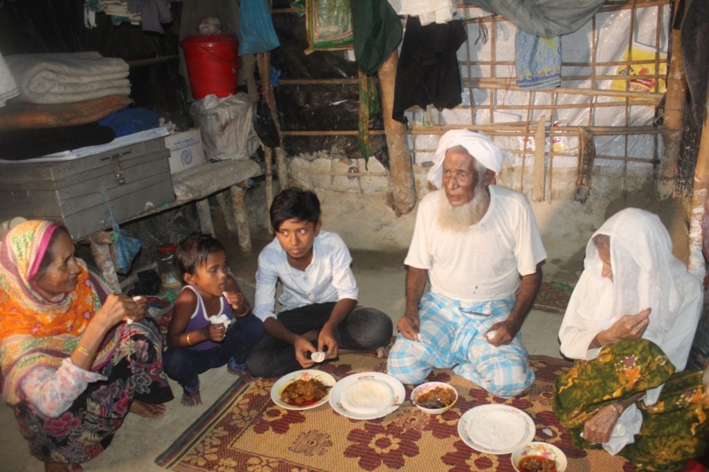 Man sits with his family in a refugee camp in Bangladesh.