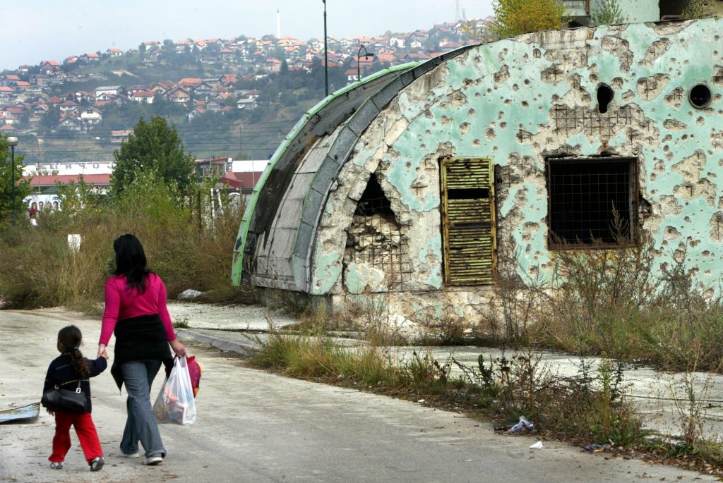 Srebrenica massacre - A woman walks with her daughter against building in Bosnia.