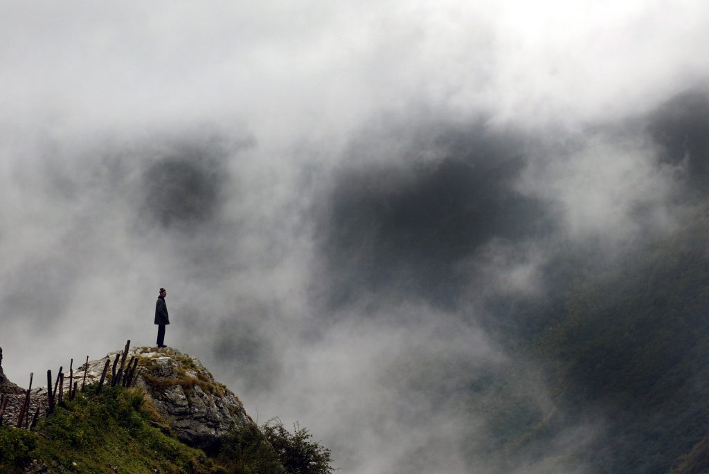 Bosnian man stand atop mountain looking over his country.