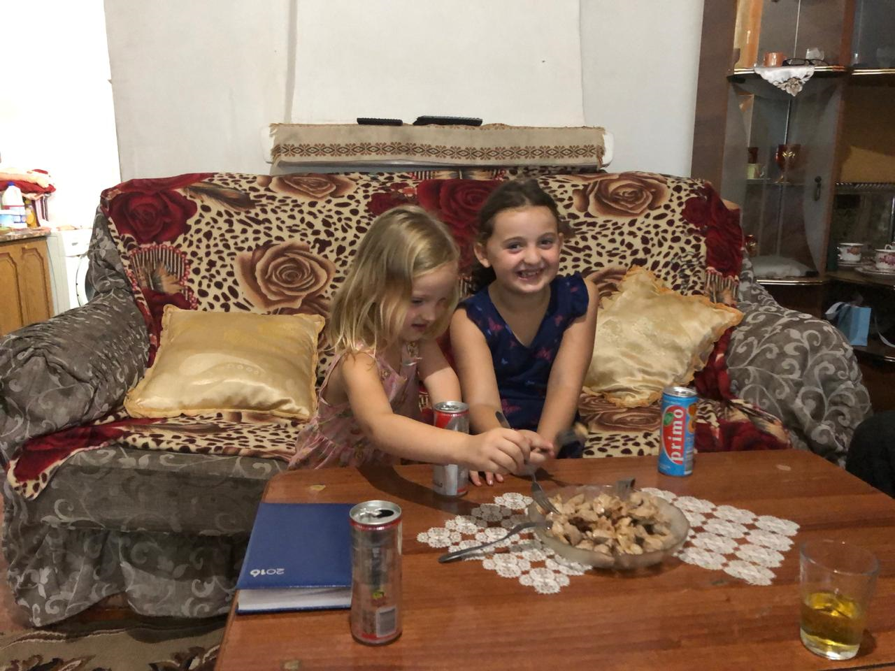 Albanian kids benefit from online qurbani canada. They are on a couch eating food.